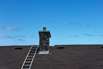 Chimney with a ladder set up for service, similar to homes throughout Bloomington, MN